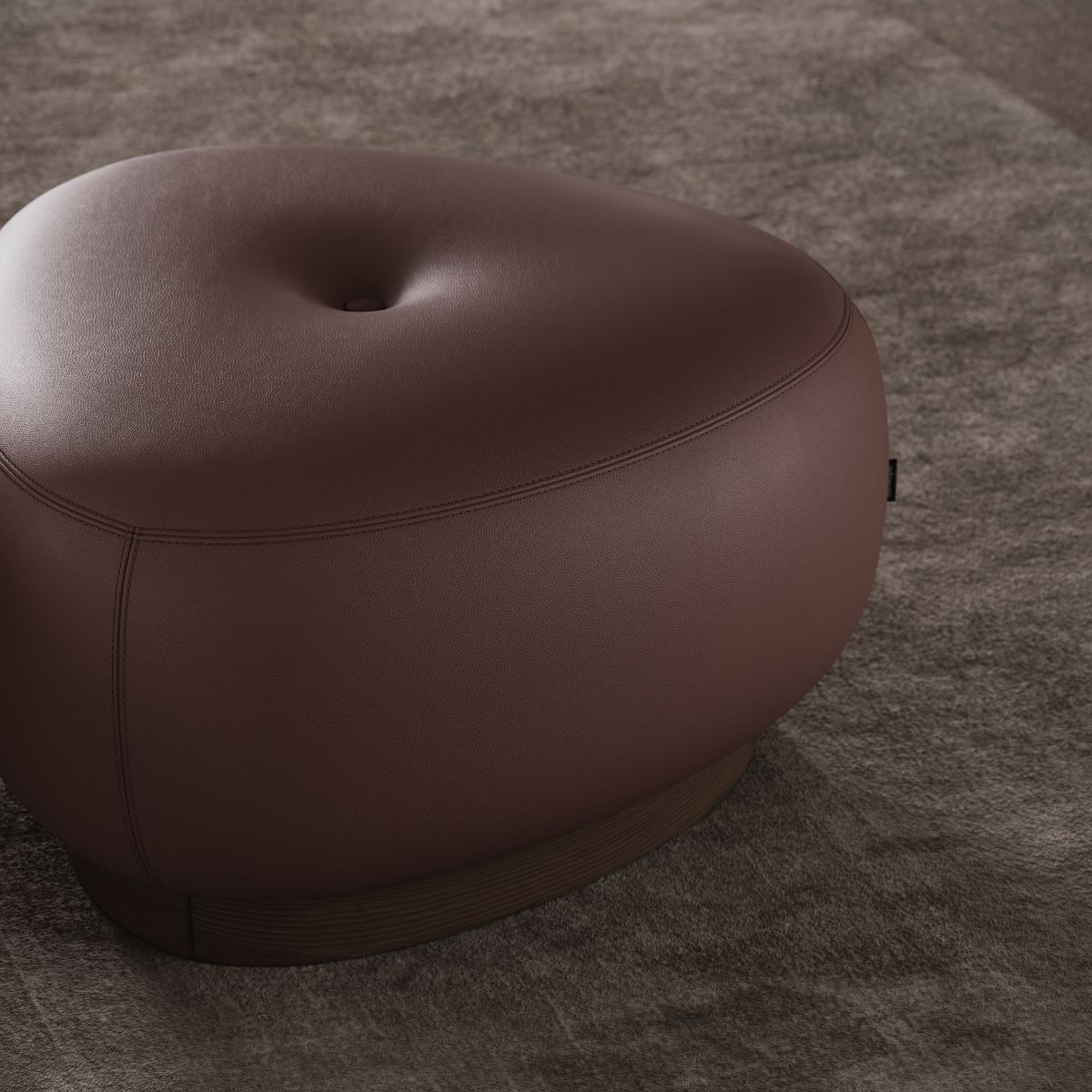 Alton Armchair by Domkapa (9) A brown leather pouf placed on a textured carpet, creating a cosy and stylish living space.