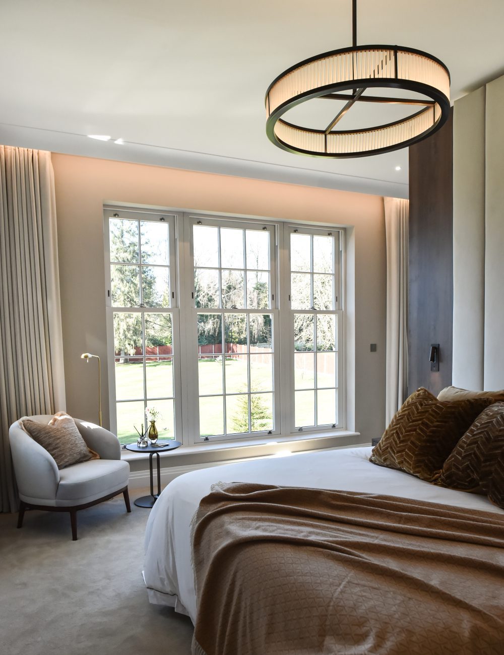 Ana Frantz Photography - Ruth Armchair in Casa More project A bright master bedroom design with a large bed, adorned with colorful bedding and surrounded by warm lighting.