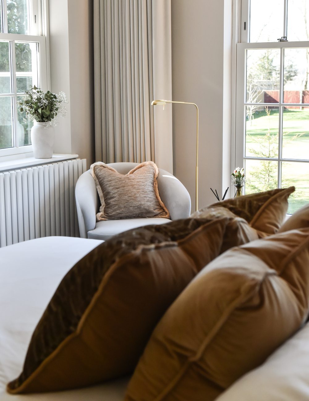 Ana Frantz Photography-ruth armchair design A tranquil master bedroom design scene with a bed, a chair, and a window that offers a view outside.