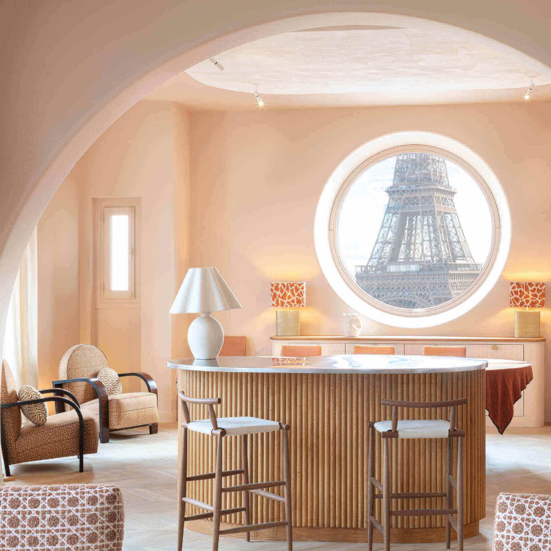 Anne-Sophie Pailleret An Anne-Sophie Pailleret project in salmon tones with wood accents in the balcony and chairs. With a round window with a view to the Eiffel Tower.