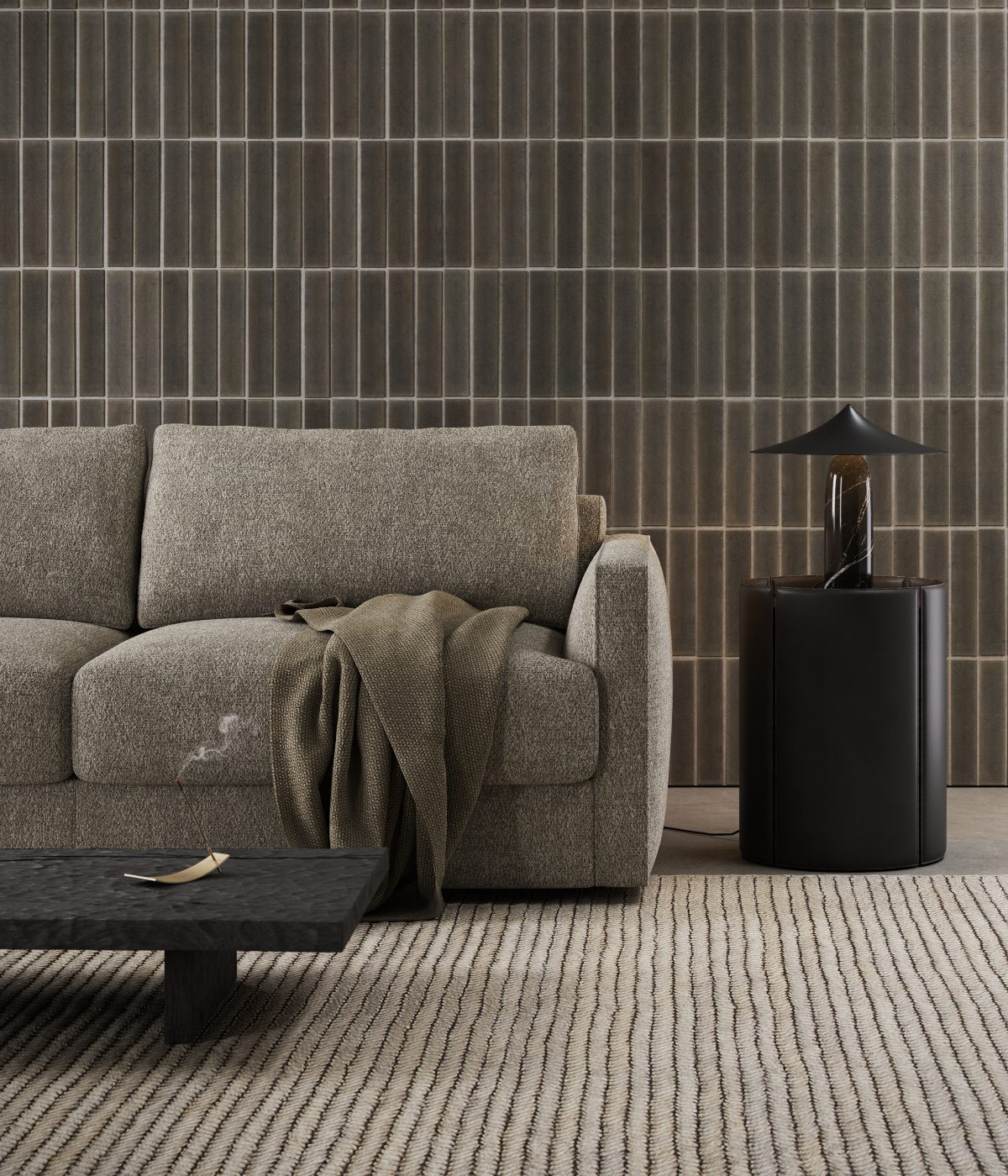 Beaumont sofa bed and Mano side table Living room with a grey sofa bed with a cosy blanket laying on top of it. With a side table upholstered in black leather and a small lamp.