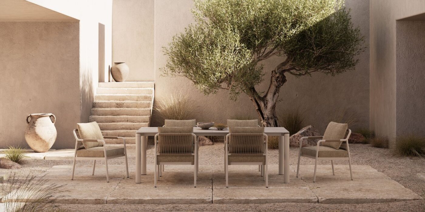 Blog Featured Image - 2026-05-14T155853.720 Outdoor patio scene with a modern dining set, surrounded by a minimalist beige wall. An olive tree and pots add a serene, Mediterranean feel.