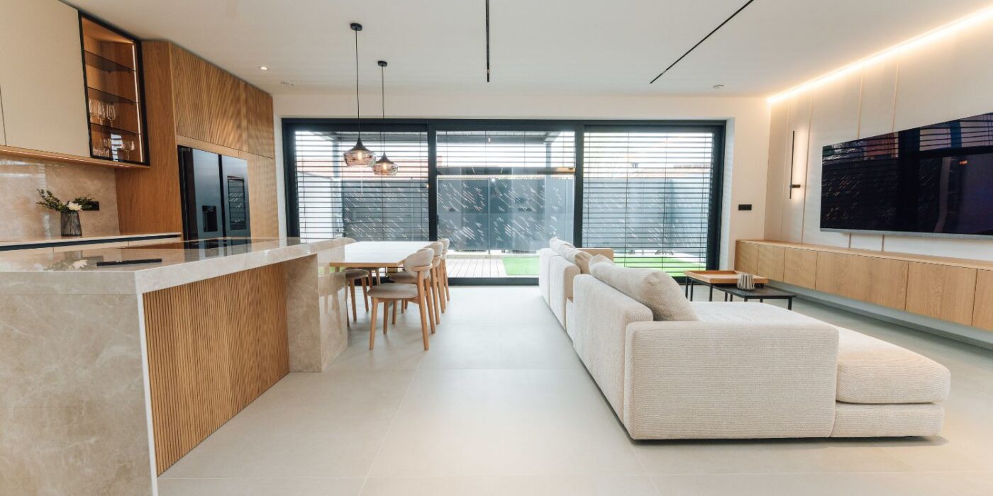 A contemporary kitchen and living room combined, featuring a wall-mounted television and modern furnishings for a cosy atmosphere.