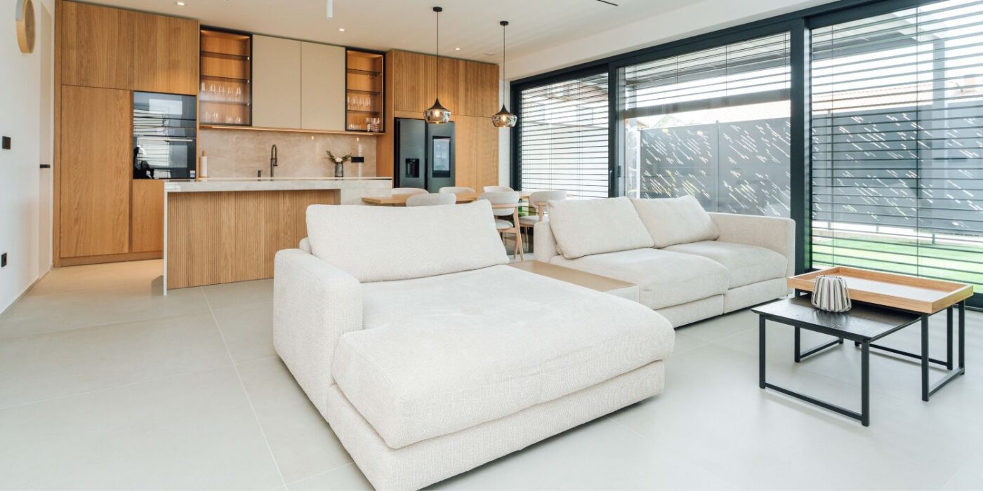 Modern living room featuring white furniture complemented by warm wooden accents. Project by Estilia Design.