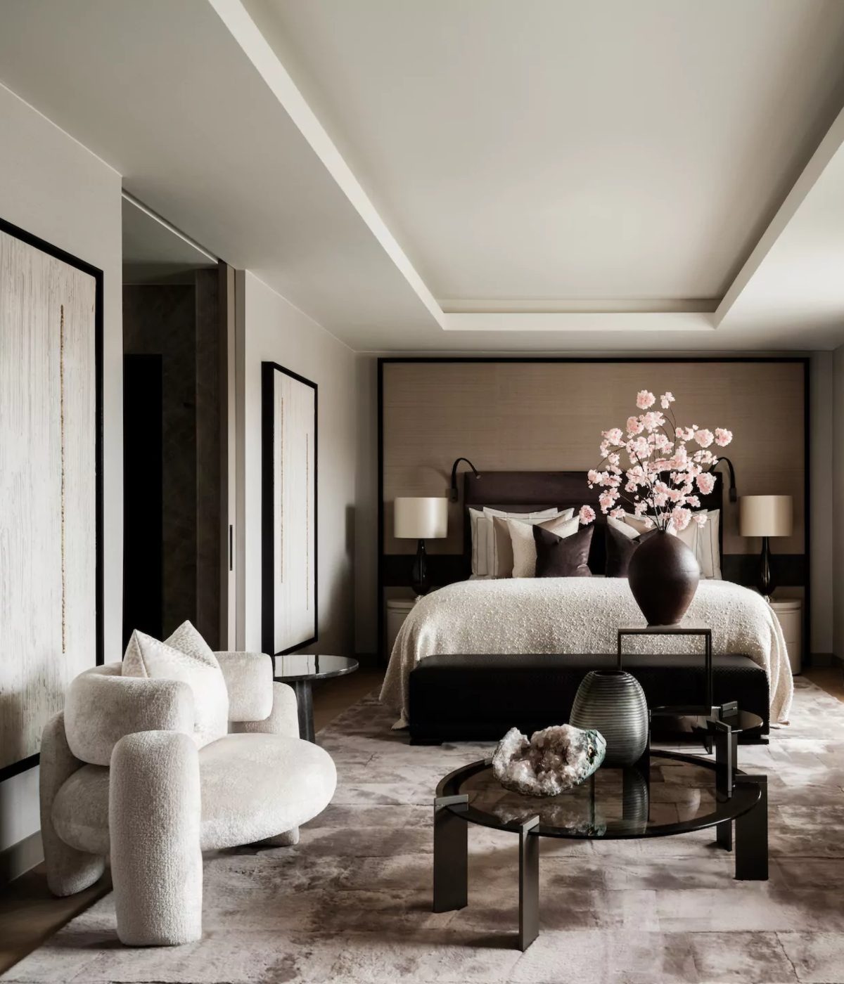 Eric Kuster Project Bedroom project with a dark brown bed and a black bench at the. With two similar white armchairs at the front corner and a coffee table in glass in the centre.