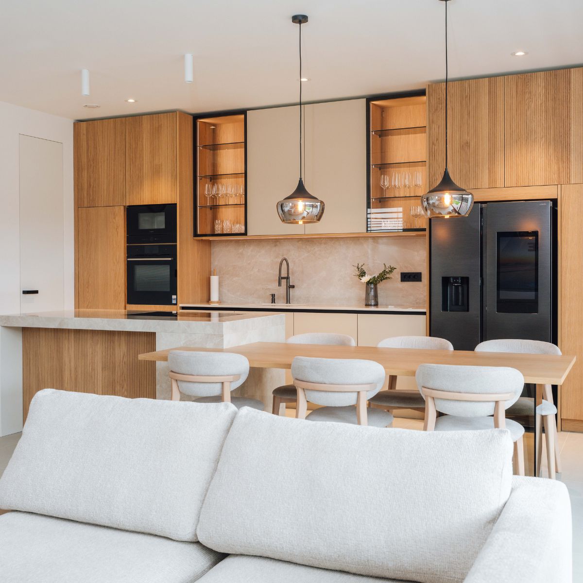 Bright modern kitchen and dining room showcasing a comfortable white sofa, perfect for relaxation and gatherings.