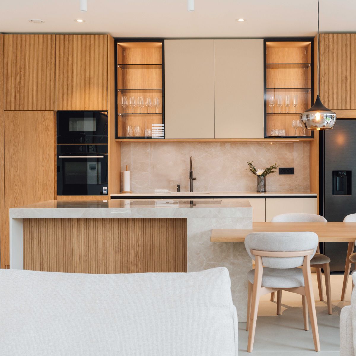 Bright modern kitchen and dining room showcasing a comfortable white sofa, perfect for relaxation and gatherings. Project by Estilia Design