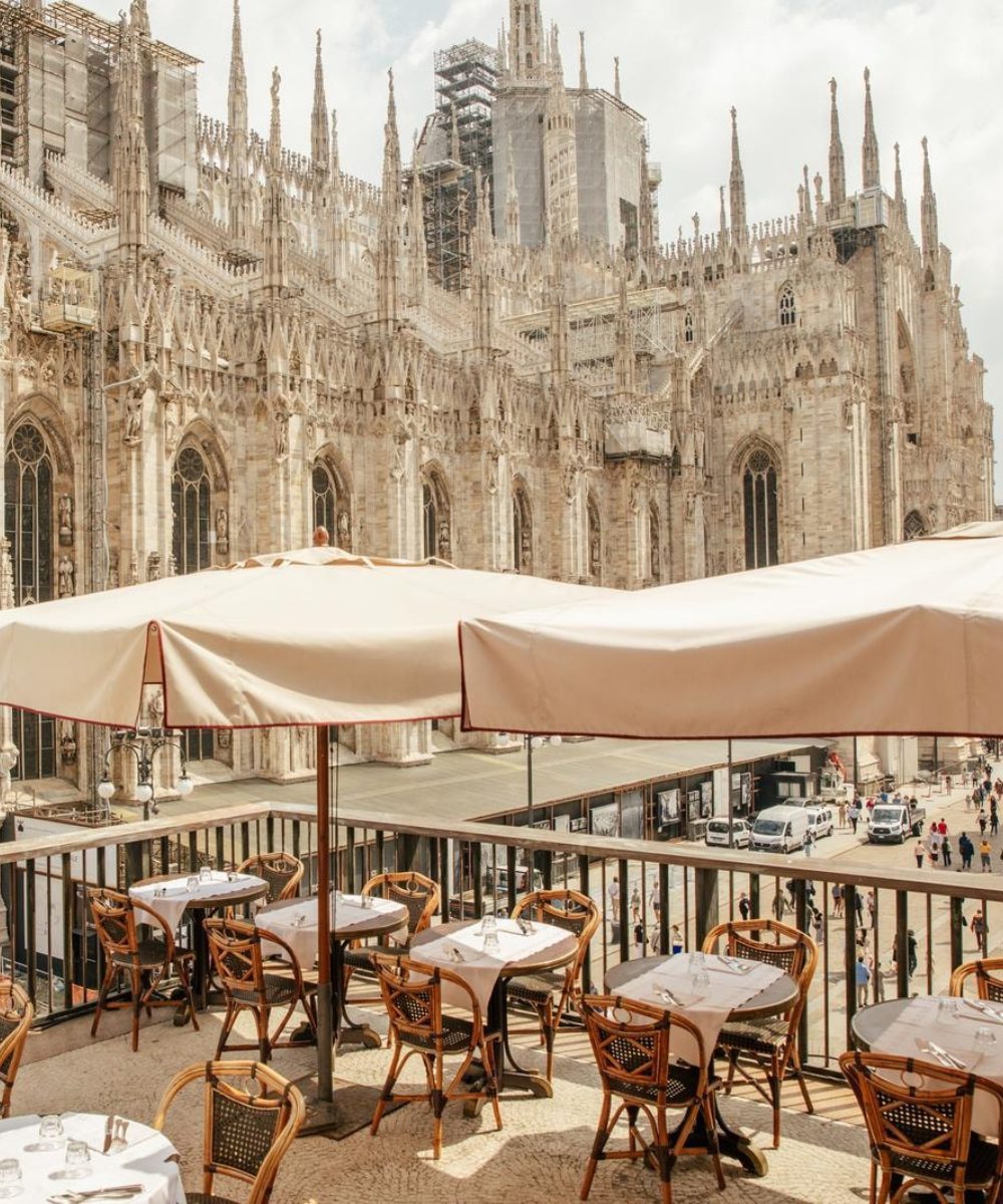 GiacomoArengario_Letiziacigliutti-626436 (1) Restaurant patio with tables and umbrellas, beautifully situated in front of a majestic cathedral in Milan.
