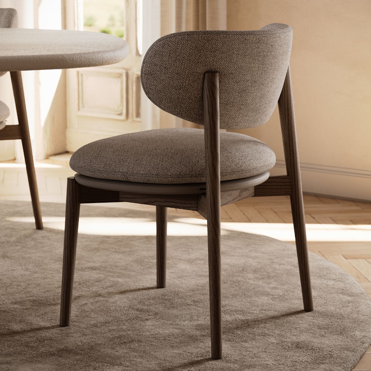 Harvey Dining Chair by Domkapa (4) Dining chair positioned in front of a round table, with a window providing natural light in the background.