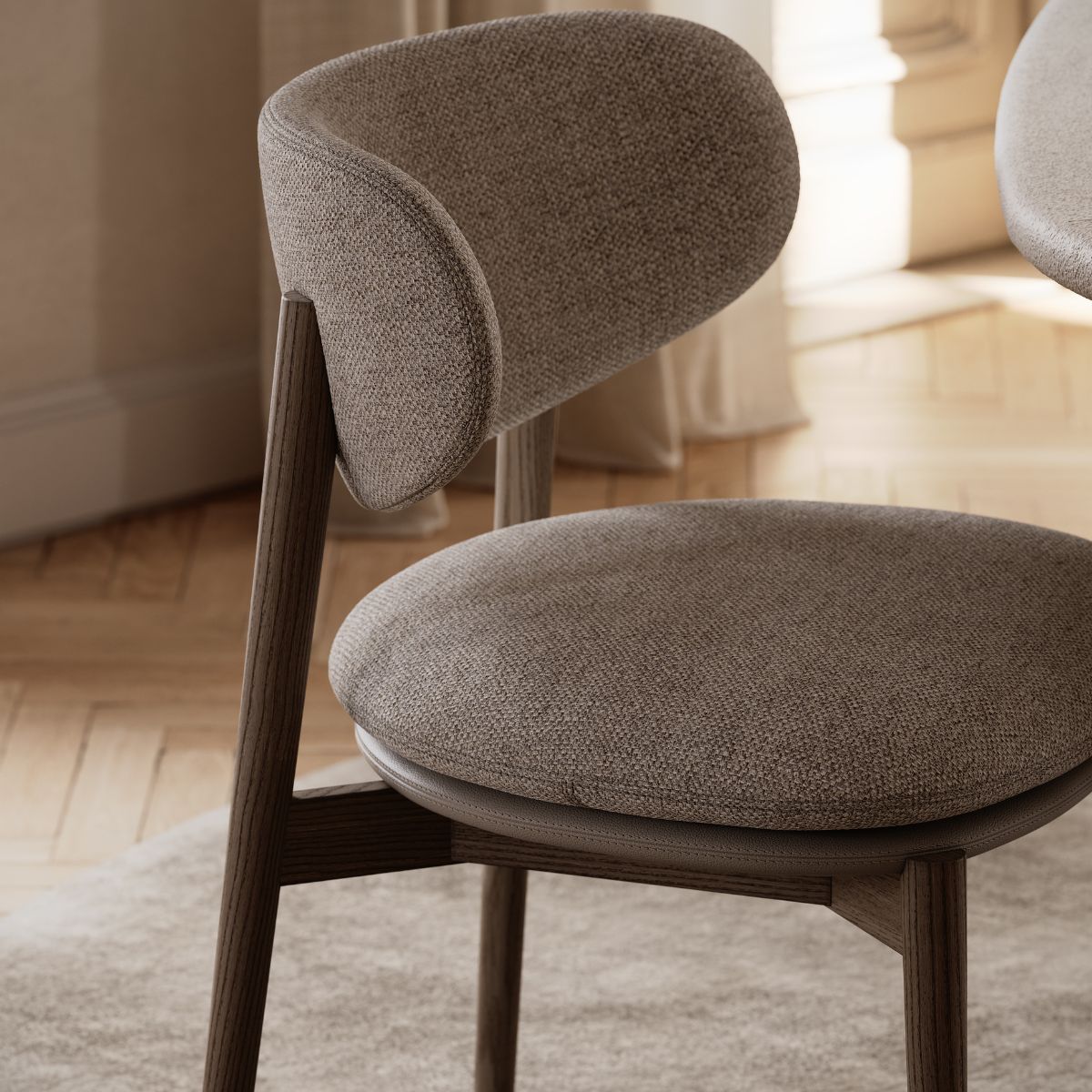 Harvey Dining Chair by Domkapa (5) A round-seated dining chair next to a wooden table, showcasing a simple and functional design for dining or workspaces.