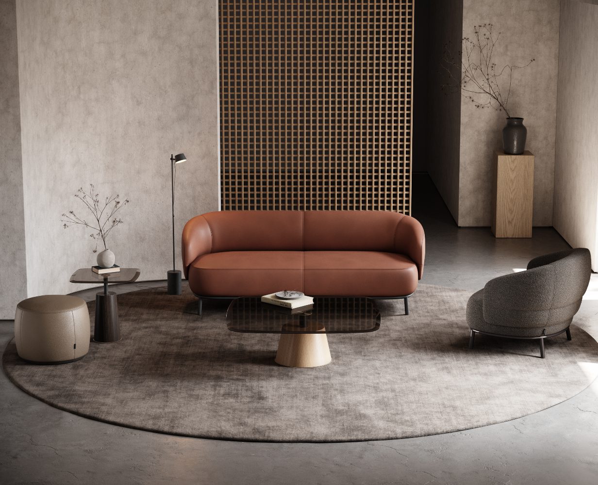 Juliet Sofa & Juliet Armchair - Custom Upholstery Living room with a leather sofa in red and an armchair in boucle. It has a pouf in light brown leather and a coffee table and side table, both in glass and wood. Custom upholstery on the sofa and armchair.