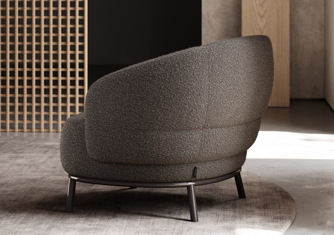 Juliet armchair by domkapa A gray armchair located in a room with a rustic wooden wall, offering a stylish and comfortable seating option.