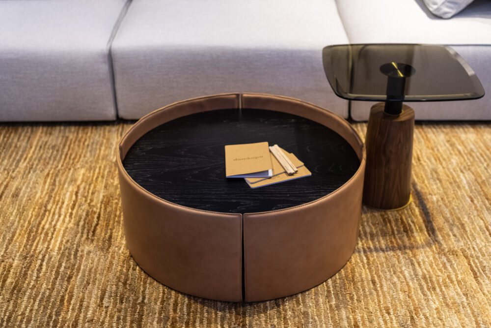 Mano and Panton table set at Decorex International A coffee table upholstered in leather and with a top in dark wood showcased at a design fair.