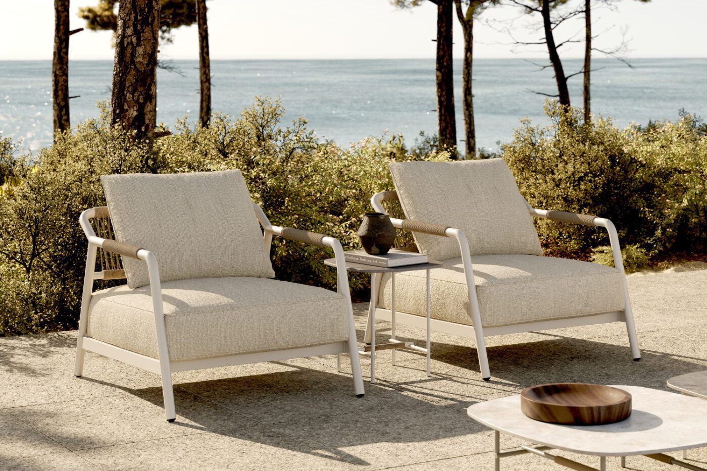 Two armchairs and a table set on a patio, with a beautiful ocean view nearby. Outdoor style by Domkapa.