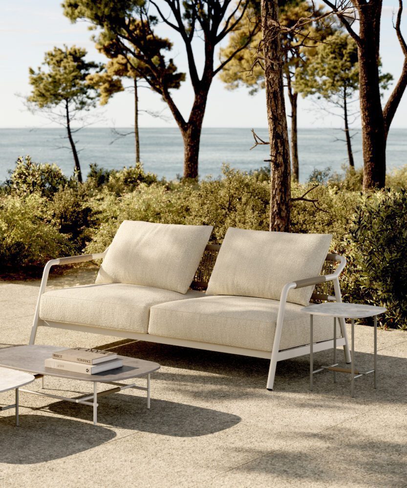 A contemporary white outdoor sofa situated on a concrete patio, inviting for outdoor style lounging.