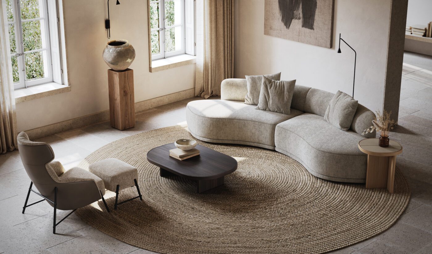 Olivia Curved Sofa A modern living room with a curved beige sofa, round coffee table, and a high-backed chair with an ottoman. Large windows let in natural light, and a textured abstract artwork hangs on the wall. Neutral tones and a woven rug complete the serene look.