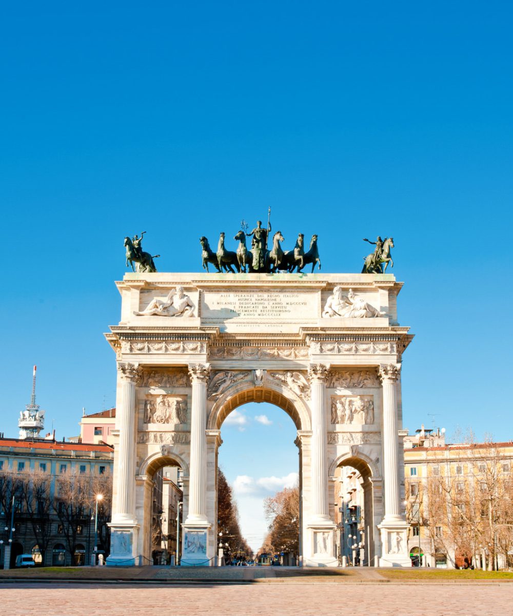 Porta Sempione (1) The Arch of Triumph in Milan, Italy, showcasing its grand architecture and intricate sculptures against a clear blue sky.
