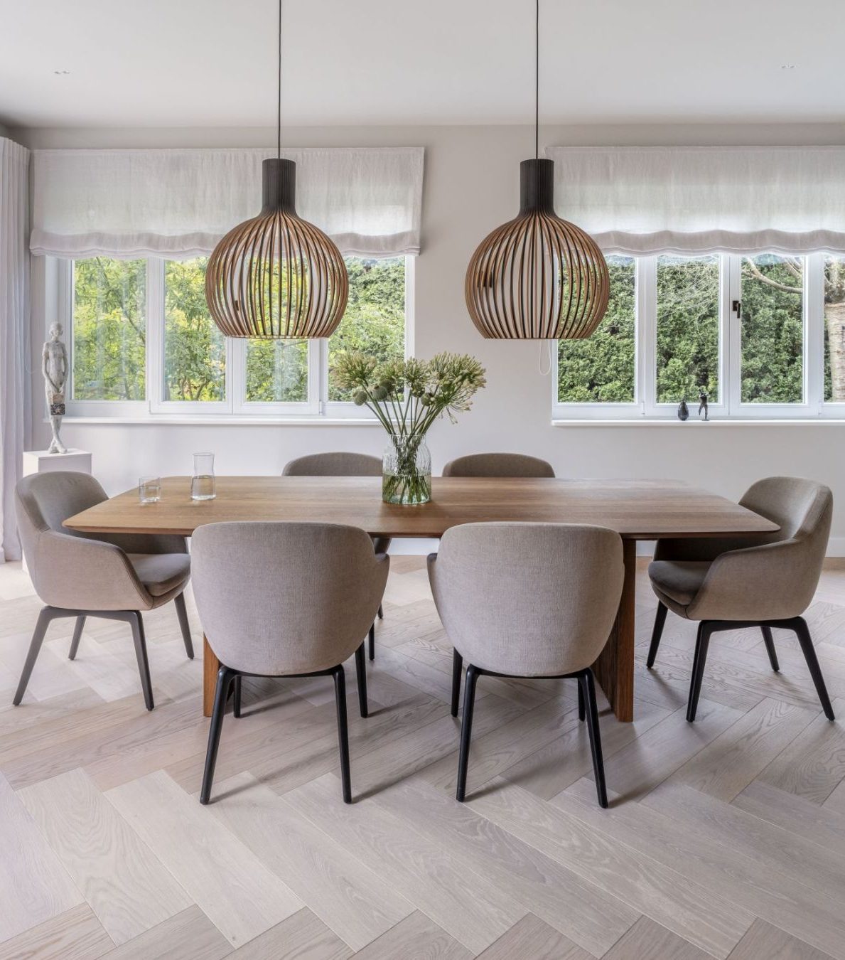 Susanne Kaiser (1) dining room with neutral toned dinig chairs and a wooden dining table. With two lighting pieces in wood.