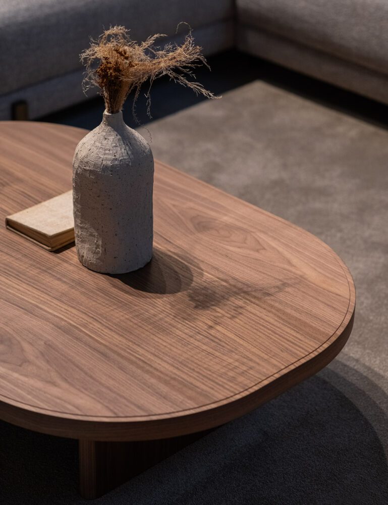 Trending materials - wood - Gilbert Coffee Table A wooden coffee table adorned with a vase, showcasing a simple yet elegant design. Sustainable wood is one of the 5 trending materials for 2025.