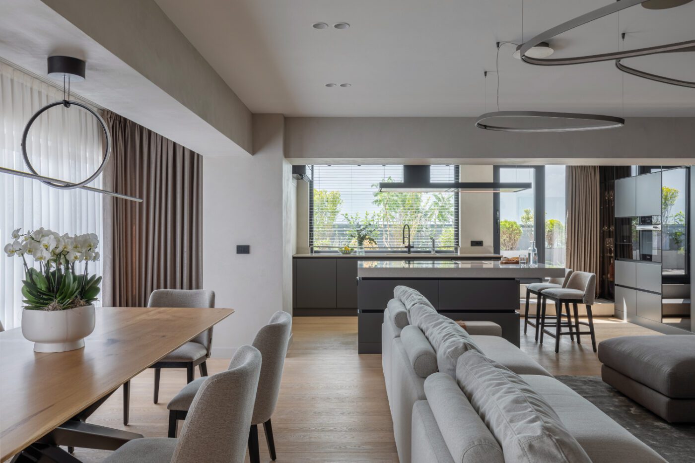 apunct studio project living area A contemporary apartment interior with a dining table and chairs, counter chairs and a modular sofa creating a warm and welcoming dining space.