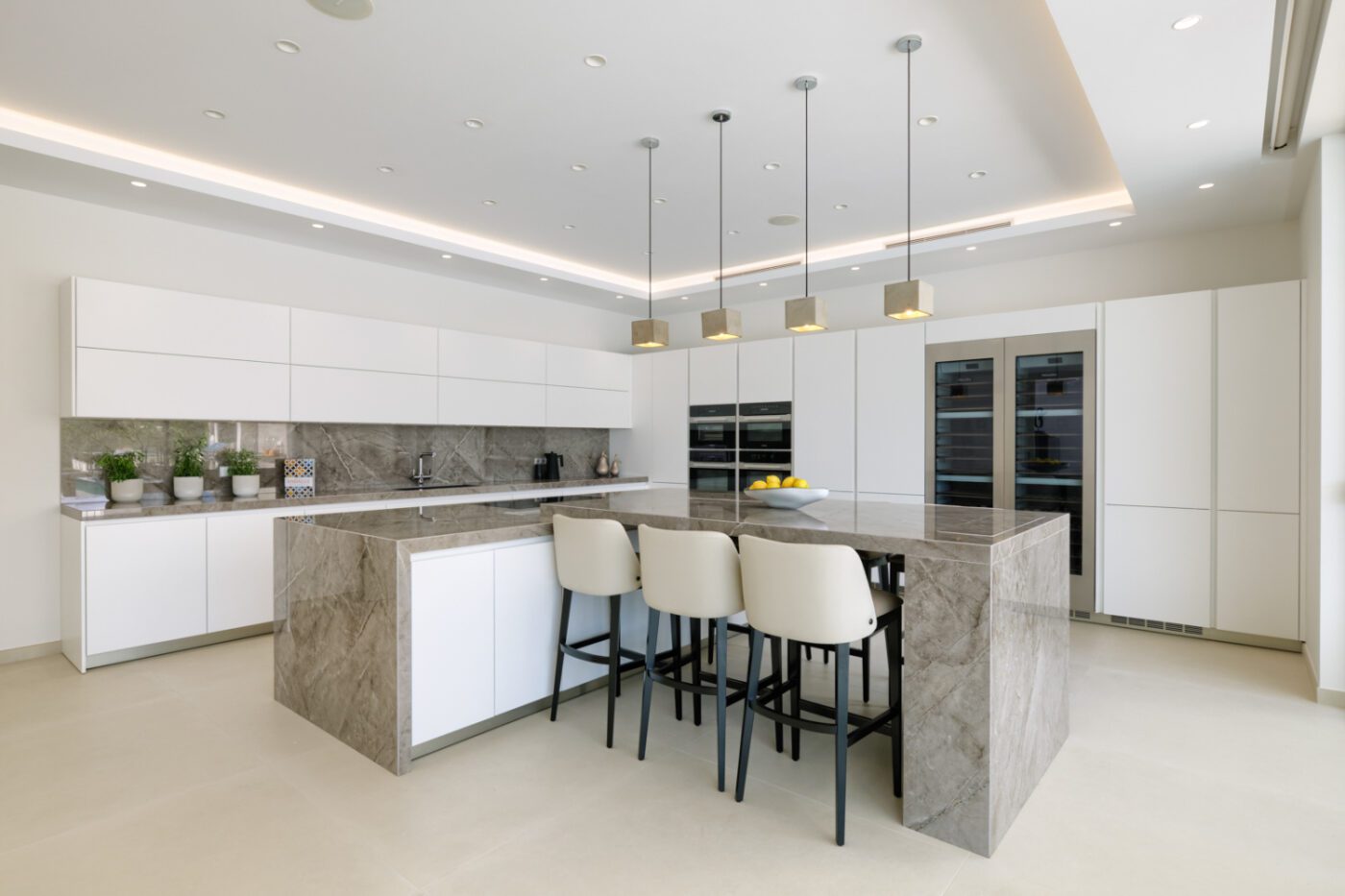 beatriz ruiperez kitchen design Contemporary kitchen with polished marble countertops and bright white cabinets forming angular lines, emphasising a stylish and spacious atmosphere.