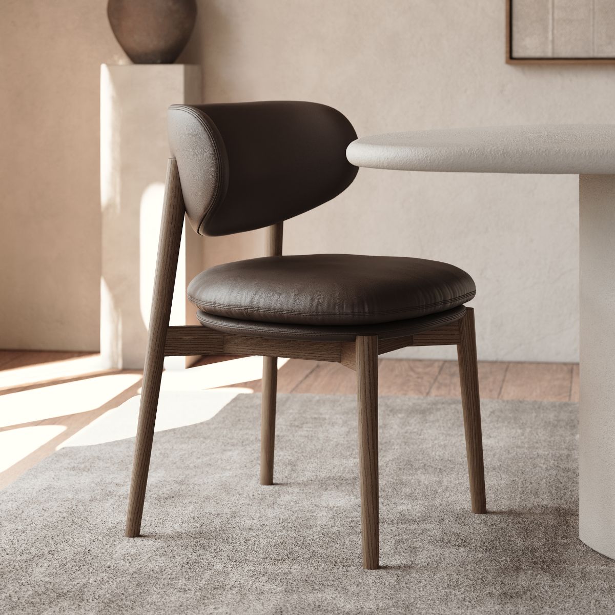 blog article about chocolate brown upholstery by domkapa (5) A chocolate brown leather seat chair positioned in front of a round table, creating a cosy dining setup.