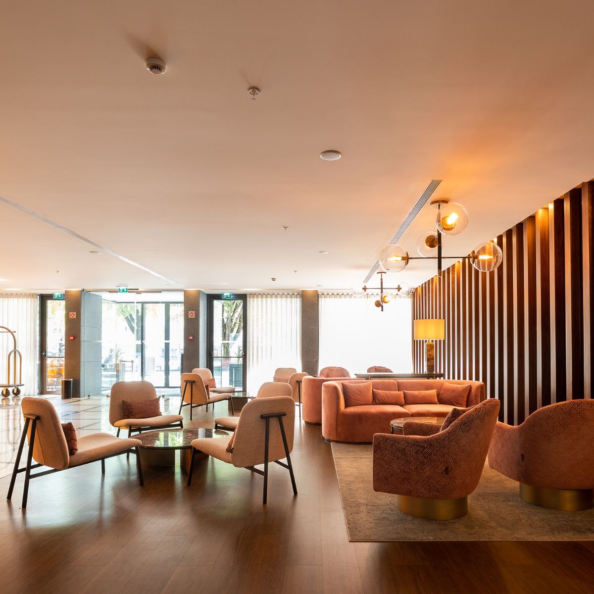 Hotel lobby featuring a large wooden wall, elegant seating, and decorative lighting, creating a welcoming atmosphere.