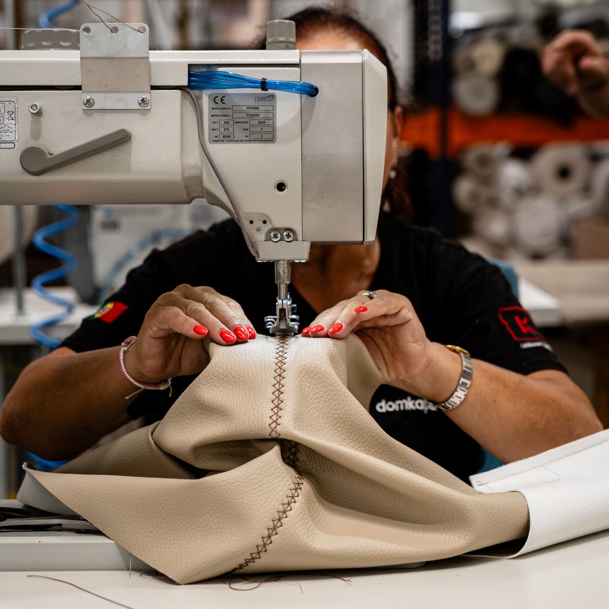 A woman sews fabric on a sewing machine, demonstrating skill and attention to detail in her craft.