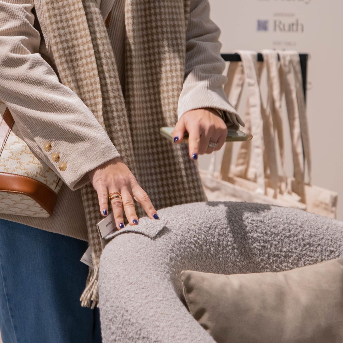 A woman displays a bag in her hand, highlighting fabric swatch selection for an armchair.
