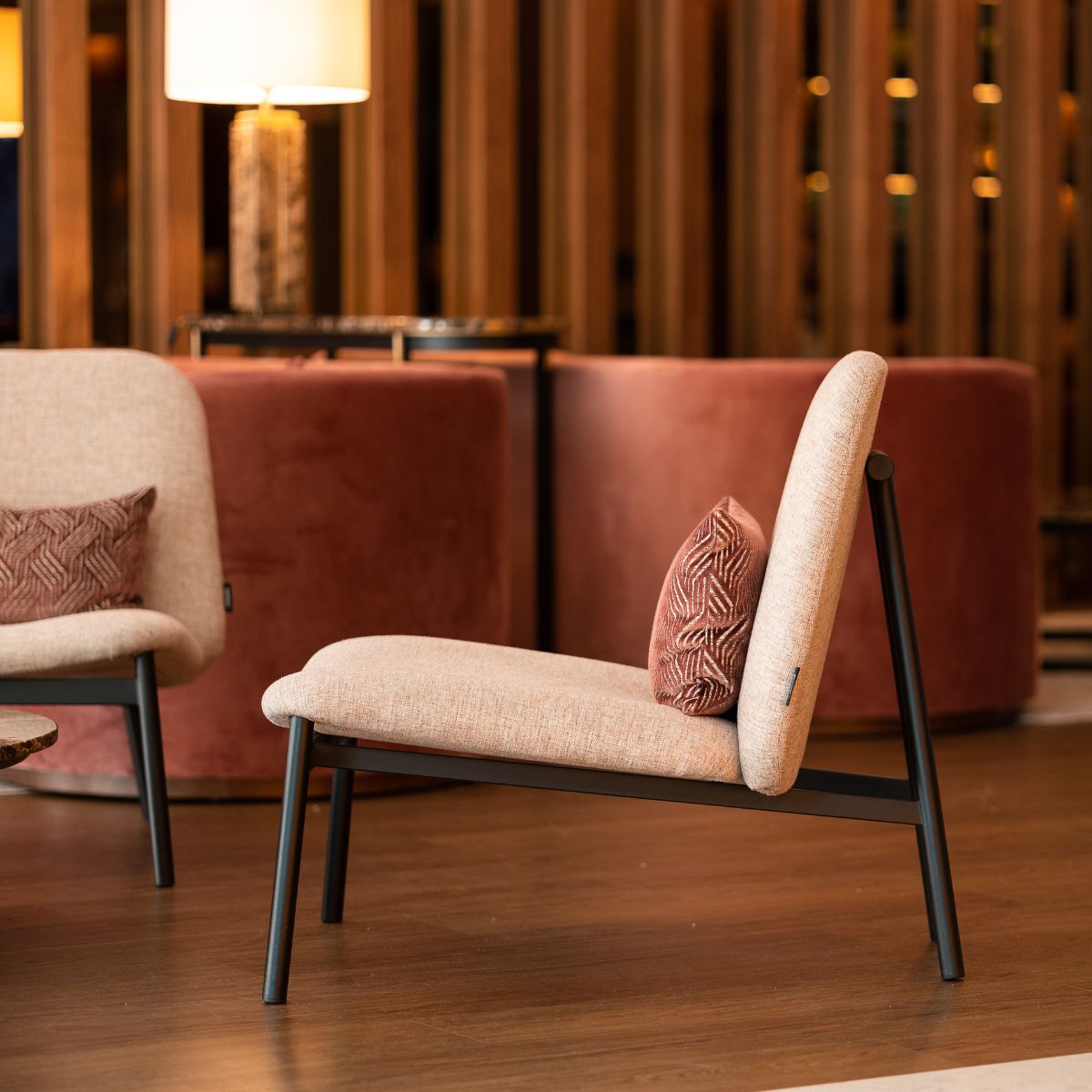 Interior view of a lounge with two armchairs, a table, and a lamp, suggesting a comfortable seating area. COM vs. house fabric