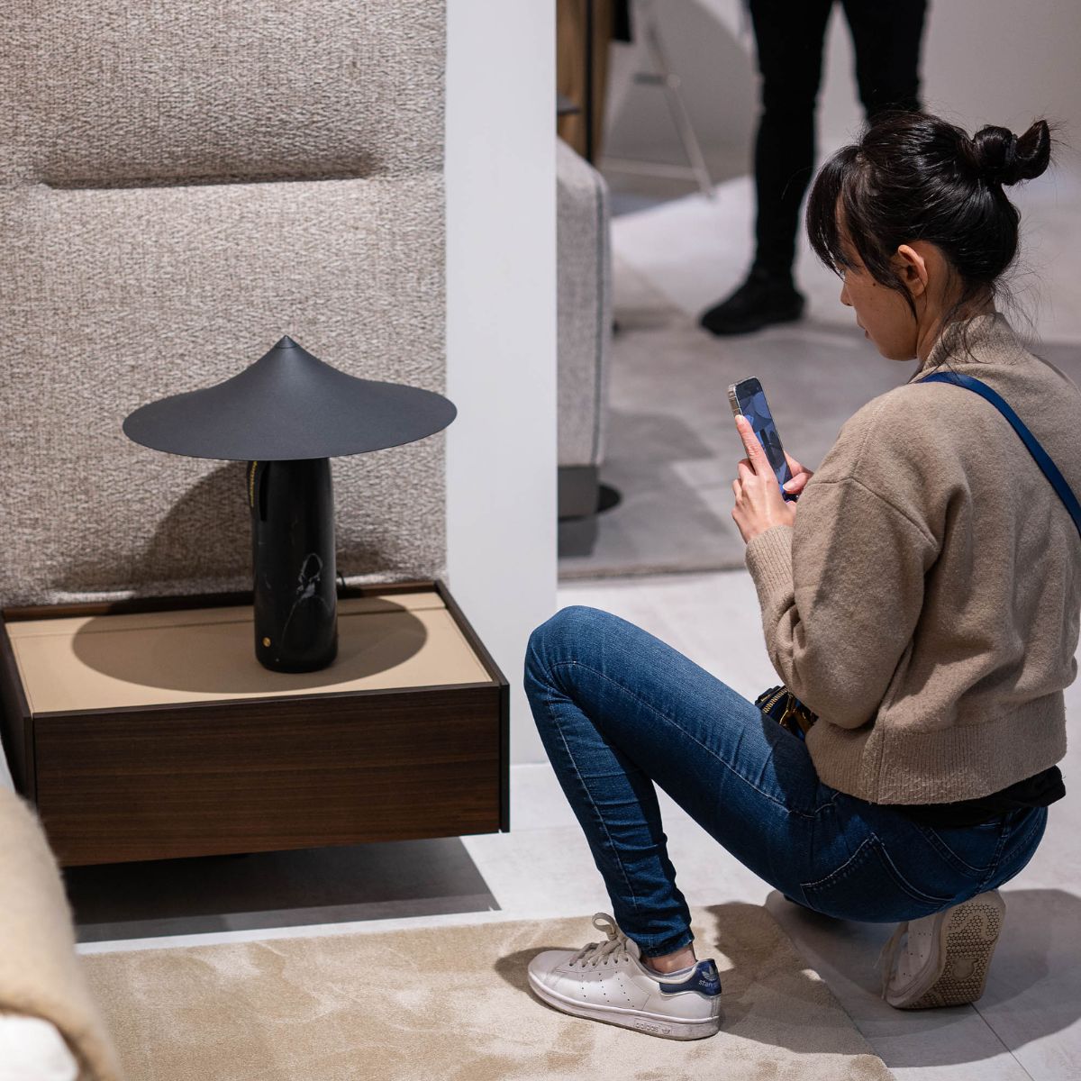 blog article about ordering furniture online by domkapa (4) A woman takes a picture of a bed with her cell phone, showcasing her interest in interior design. Ordering furniture online