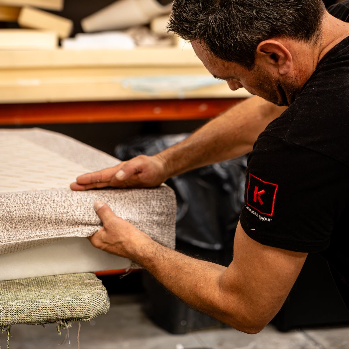 blog article about ordering furniture online by domkapa (9) A man is wearing a black shirt, works on the upholstery of a sofa.