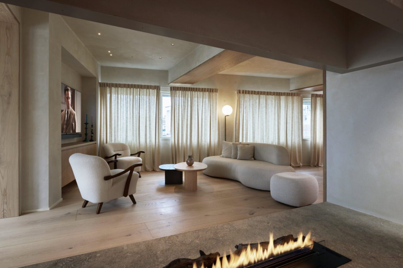 carola-vannini-parioli-penthouse-11 (1) Inviting living room with a crackling fireplace and plush chairs, perfect for gatherings and cosy evenings. From one of the 5 best italian interior designers.