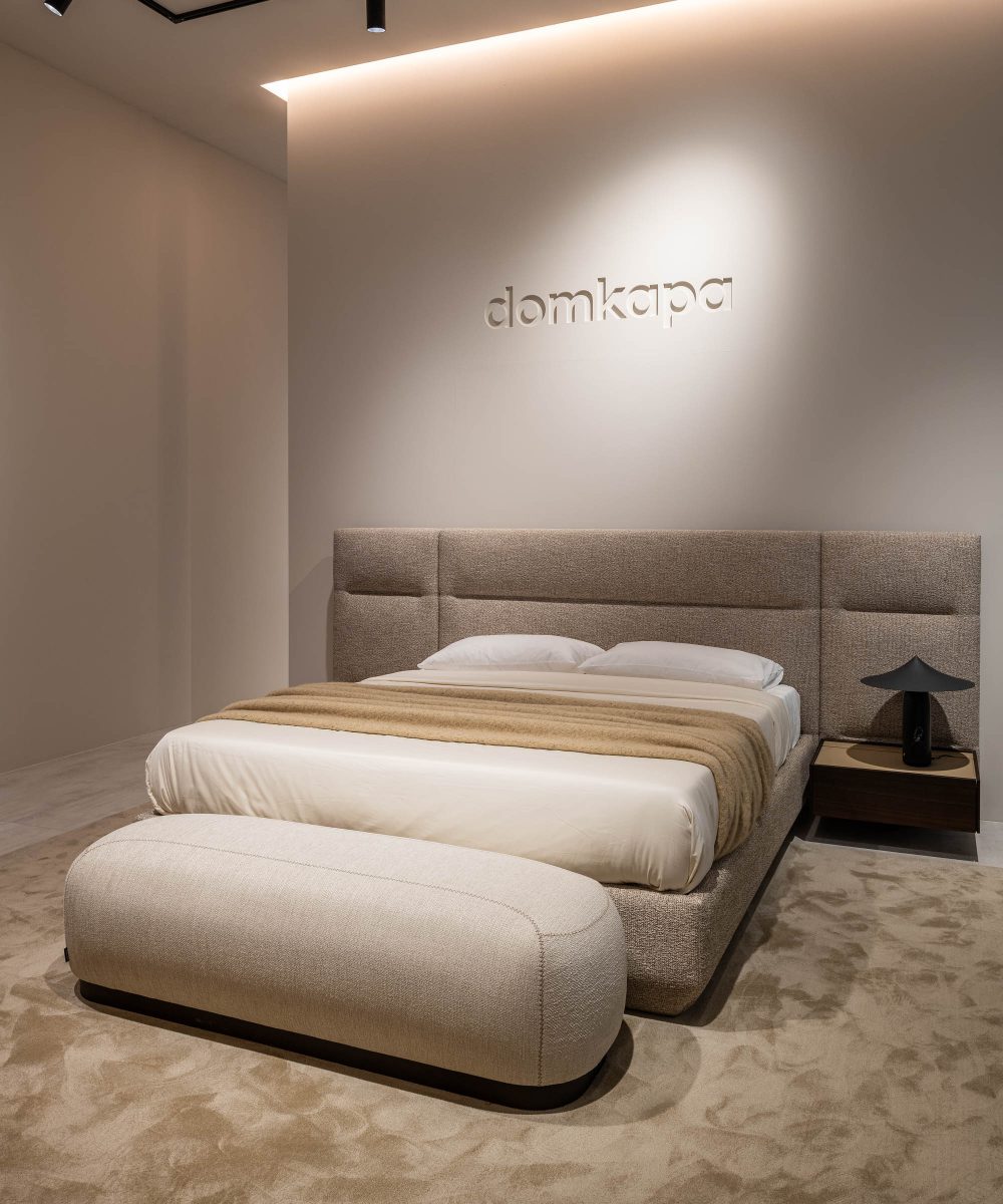 A well-arranged bed with a decorative headboard and footrest, situated in a serene room atmosphere at salone. It is a modular bed.