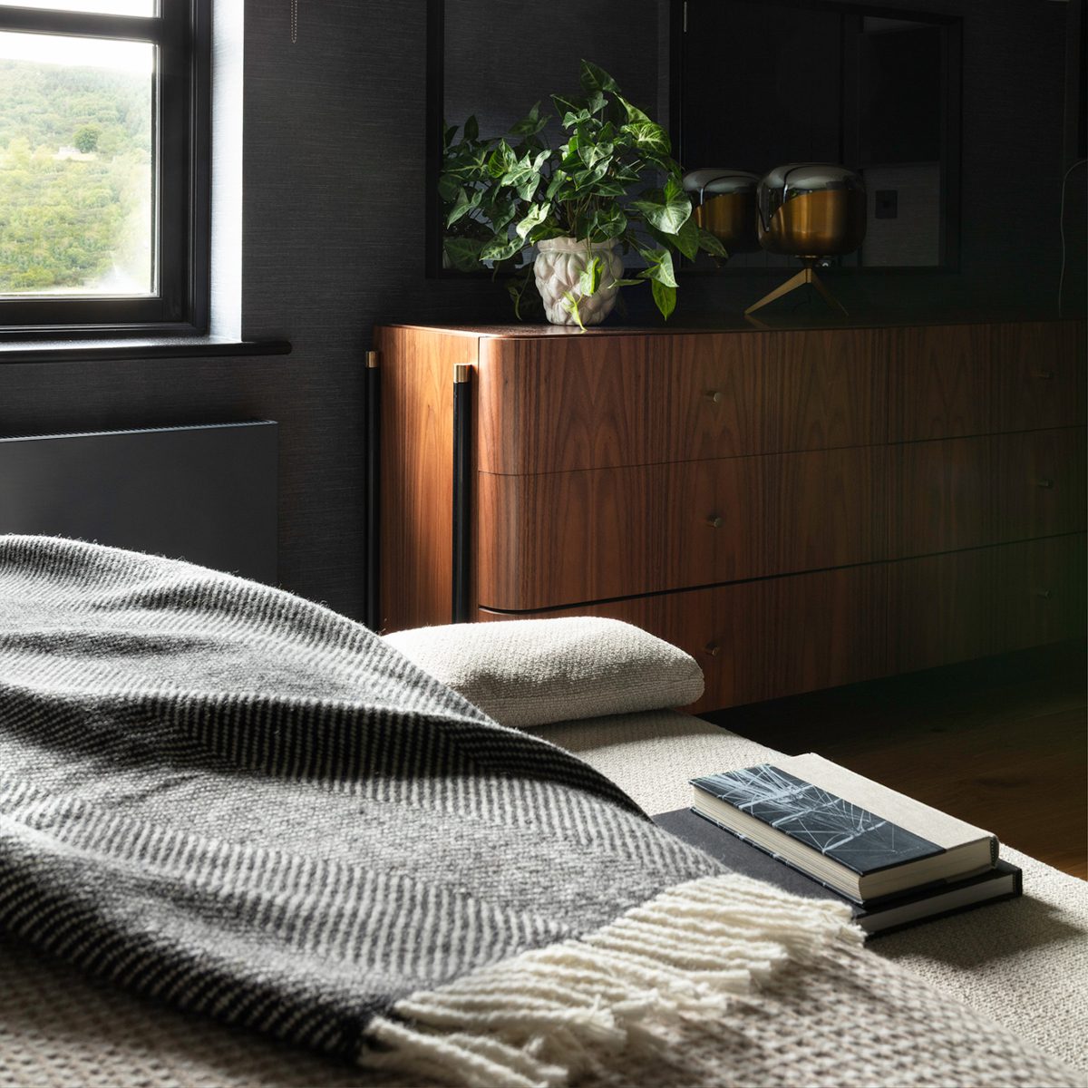 henry bench in an edit design studio project A neatly made bed with a soft blanket and a book placed on the nightstand nearby.