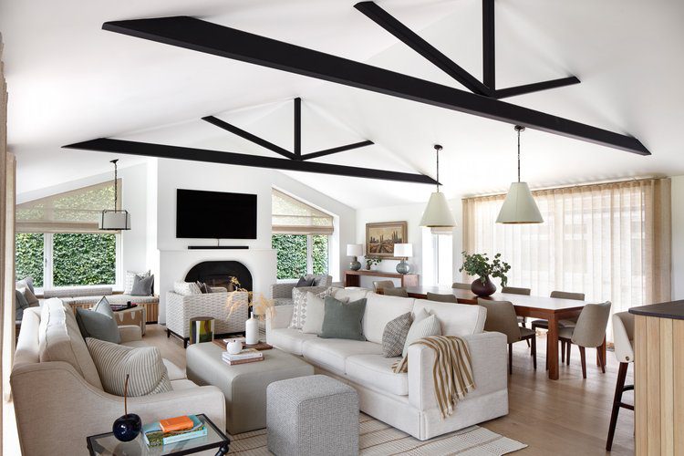 Living room by Quirc Interior Design Contemporary living room with sleek white furniture and bold black beams, enhancing the overall design aesthetic. With a white upholstered sofa and a dining table behind. The dining area has domkapa's louise chairs and the bar area has louise bar chairs.