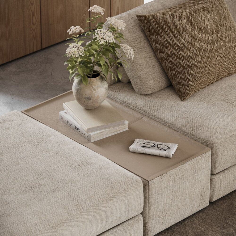A cosy beige moduçar sofa features a vase of white flowers, a book, and glasses on a side table. A brown patterned cushion adds warmth. Interior design trends for spring 2026