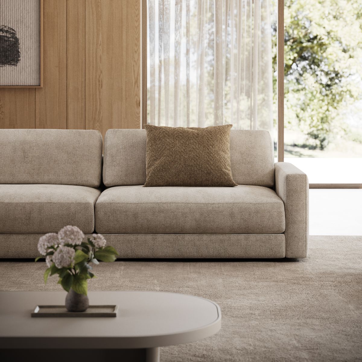 Modern living room with a beige modular sofa, accented by a brown pillow. A flower vase sits on a coffee table, and a large window shows trees outside. Interior design trends for spring 2026