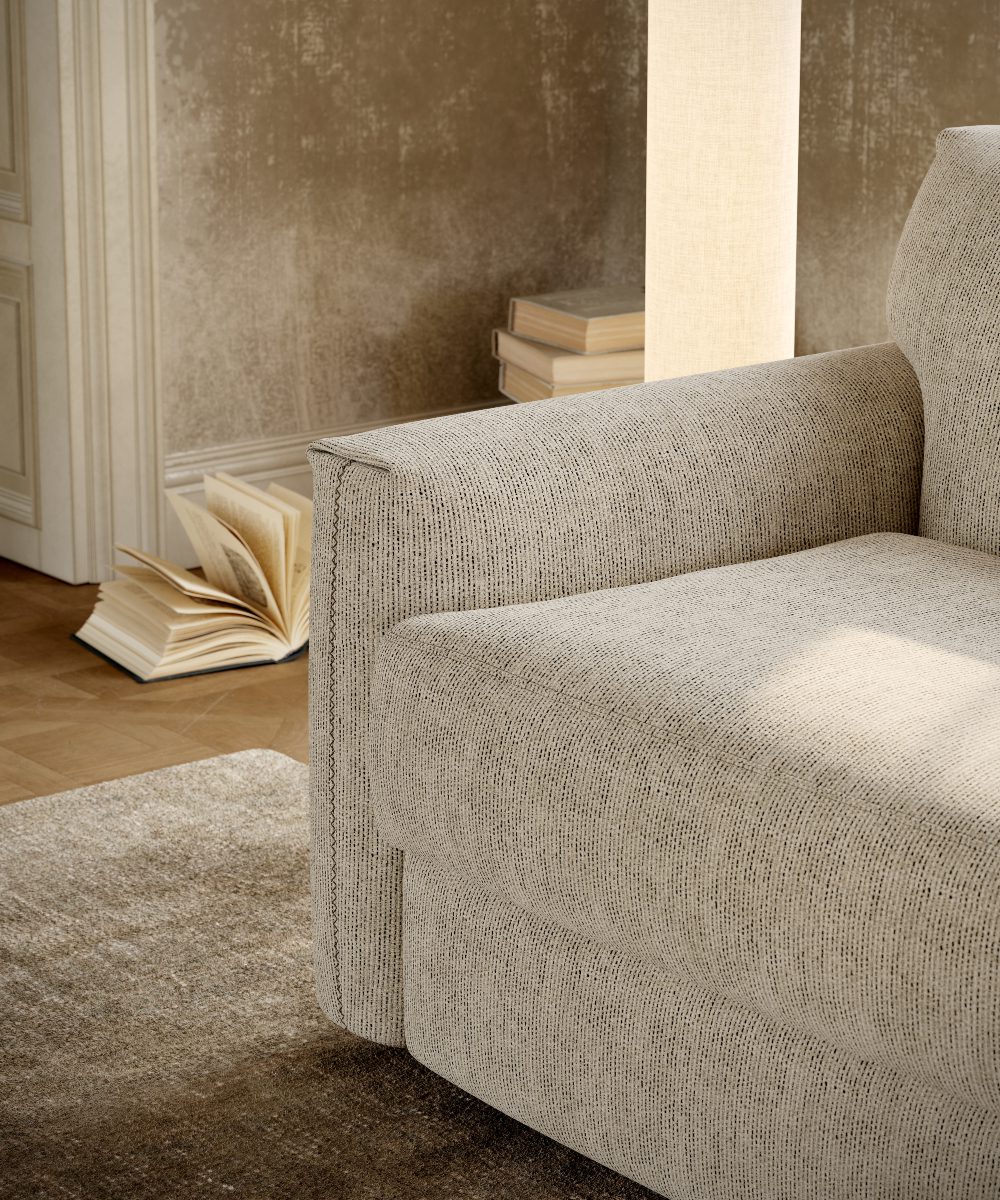 jacques sofa details A comfortable sofa bed sits in a living room, with a book resting on the floor beside it.