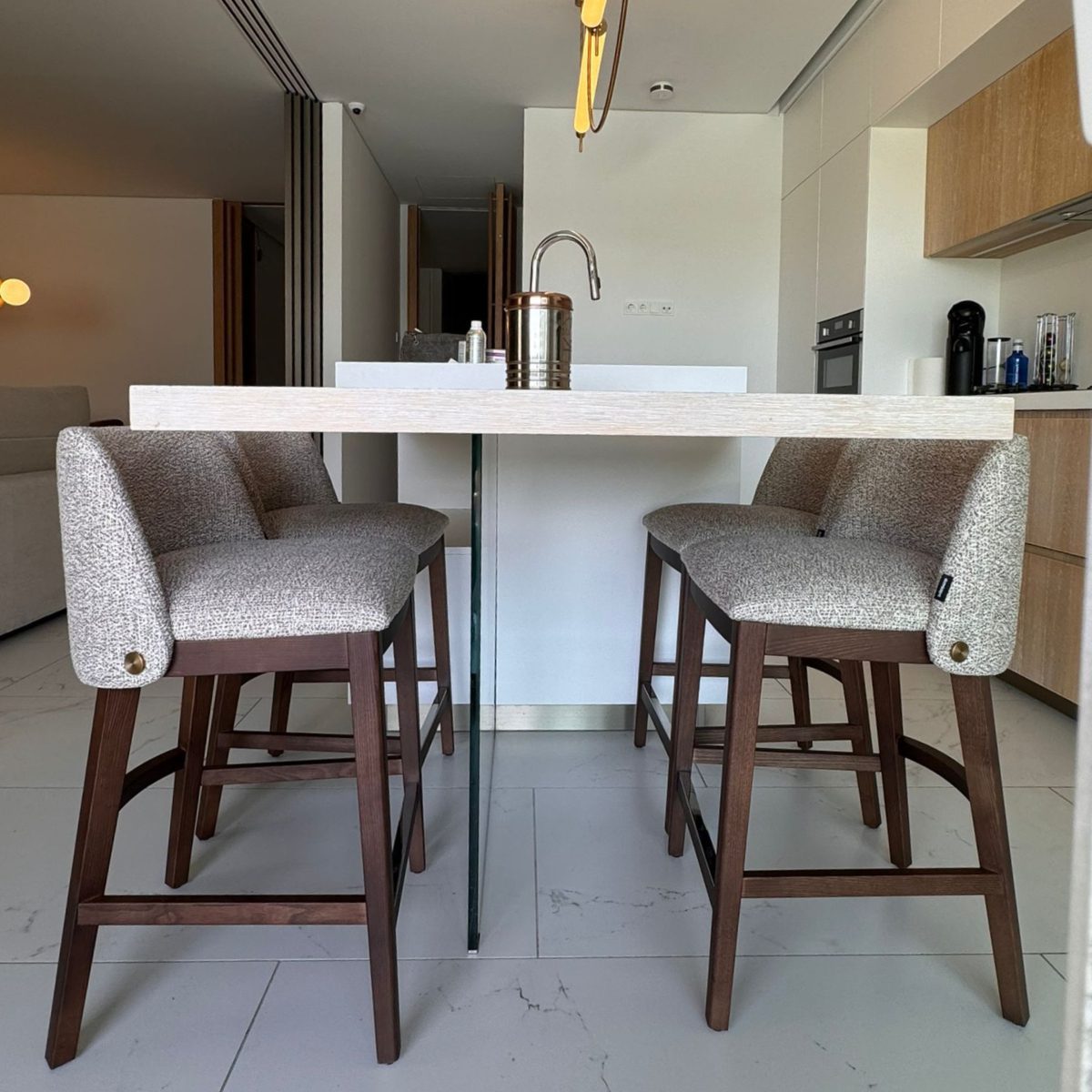 louise counter chair at lucia hidalgo project A kitchen scene featuring a table with four counter chairs and a sink, ideal for meals and food preparation.