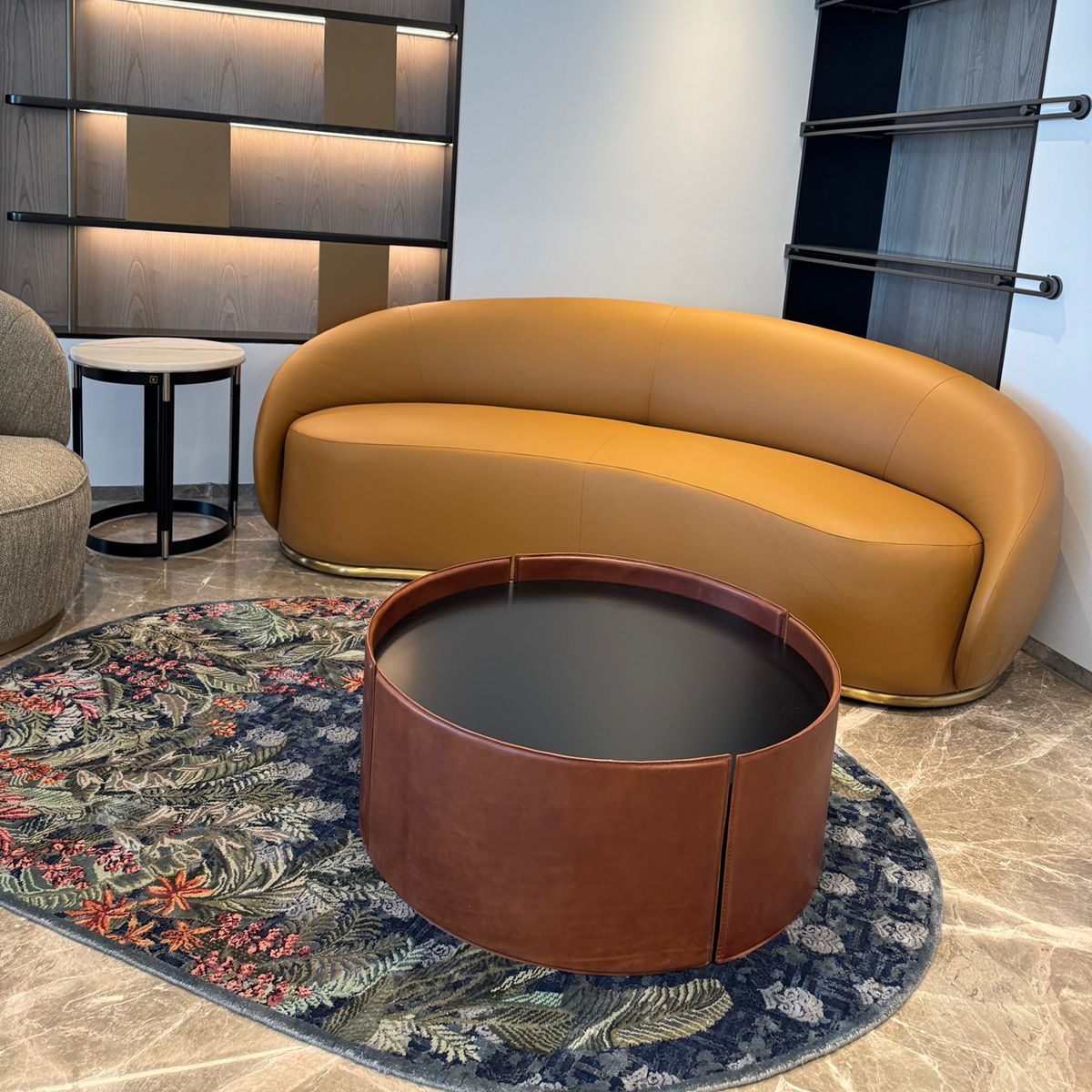 mano coffee table in a living room project A modern living room featuring a round sofa and a leather coffee table, creating a cosy and inviting atmosphere.