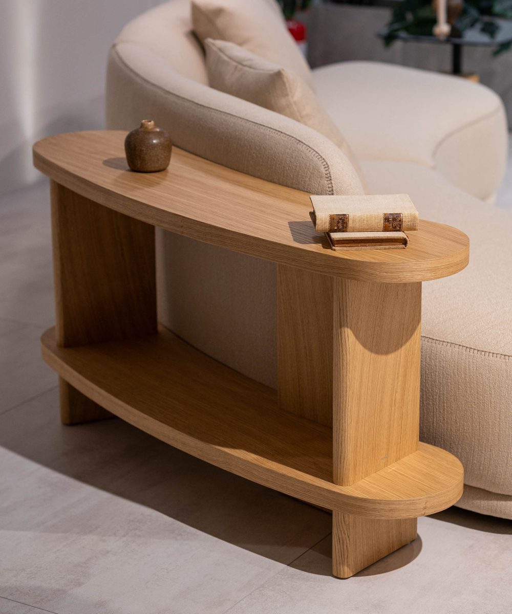 A wooden table featuring an open book resting on its surface. A new module for the Olivia modular sofa.