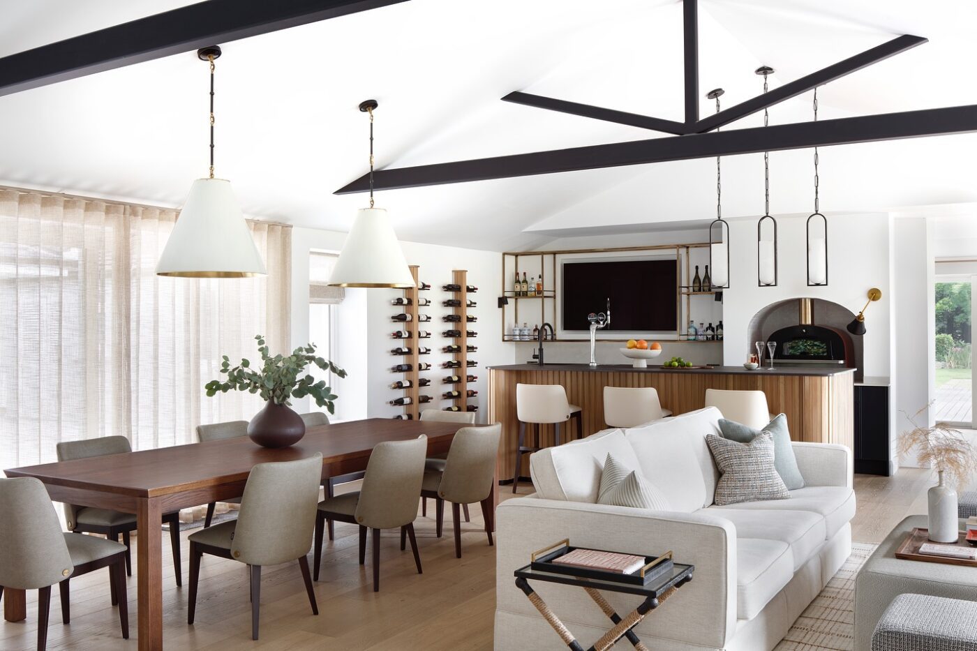 quirc dining and kitchen An elegant space with a dining table and chairs, designed for comfort and dining experiences. With a bar with white bar chairs, matching the grey chairs.