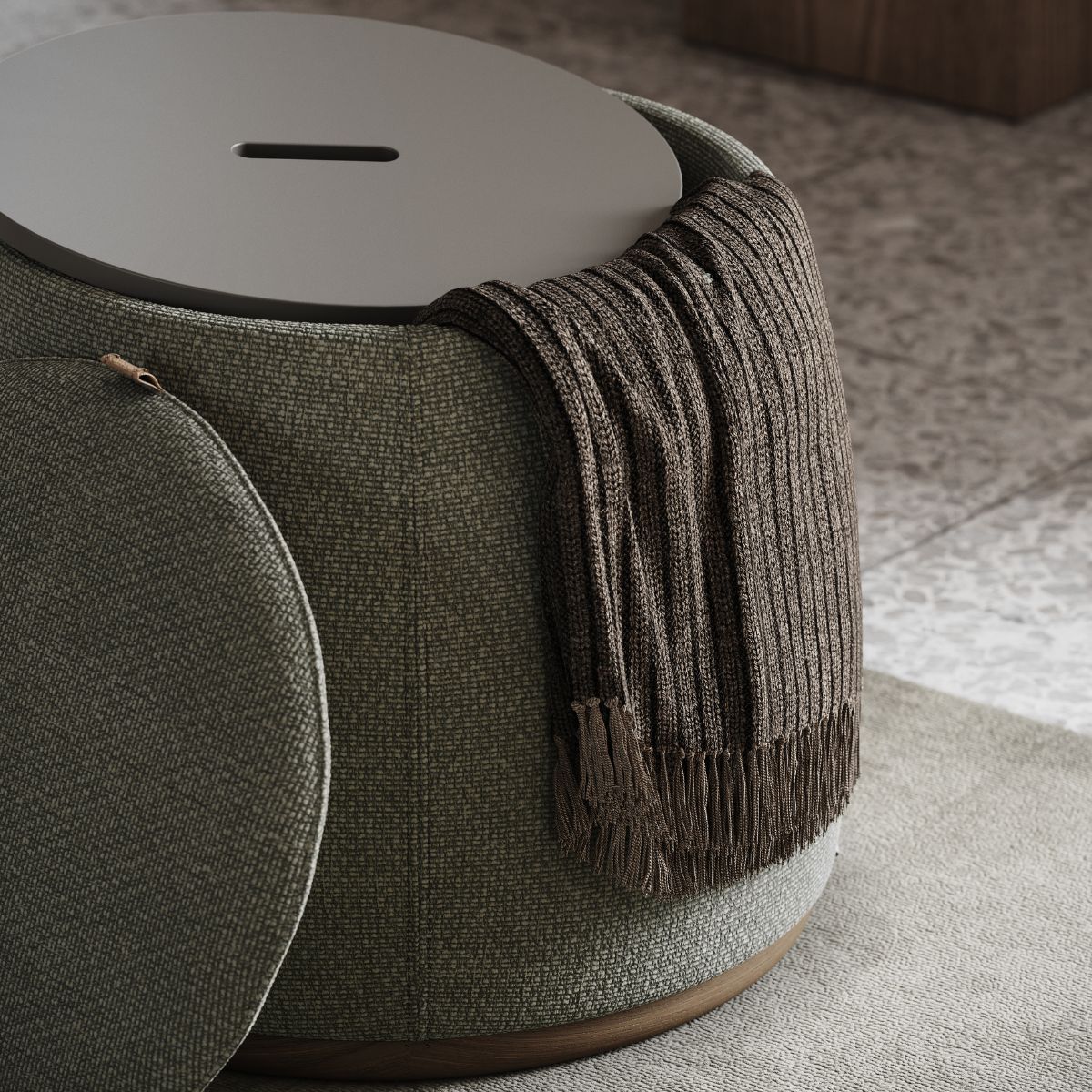 A green upholstered pouf with a brown knit throw draped over it, set on a patterned tile floor. The scene conveys a cosy, inviting atmosphere.